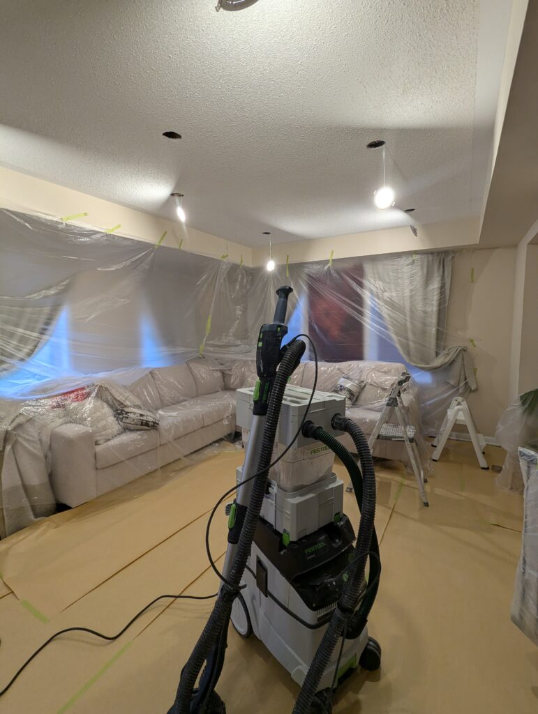 Festool dustless vacuum system used during popcorn ceiling removal with furniture professionally covered
